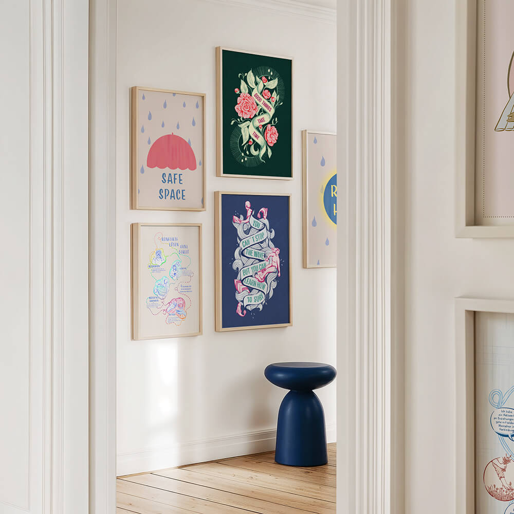 Foto eines hellen, modernen Wartebereichs, Man sieht eine Gallery Wall mit großformatigen, gerahmten Kunstdrucken mit Sprüchen: save Space, Good Things take time, You can´t stop the wave, but you can learn how to surf und ein Druck zum Thema gewaltfreie Kommunikation. Darunter steht ein blauer Hocker.