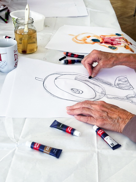 Man sieht die Hände von an Parkinson erkrankten Menschen die bei einer Kunsttherapie zeichnen.